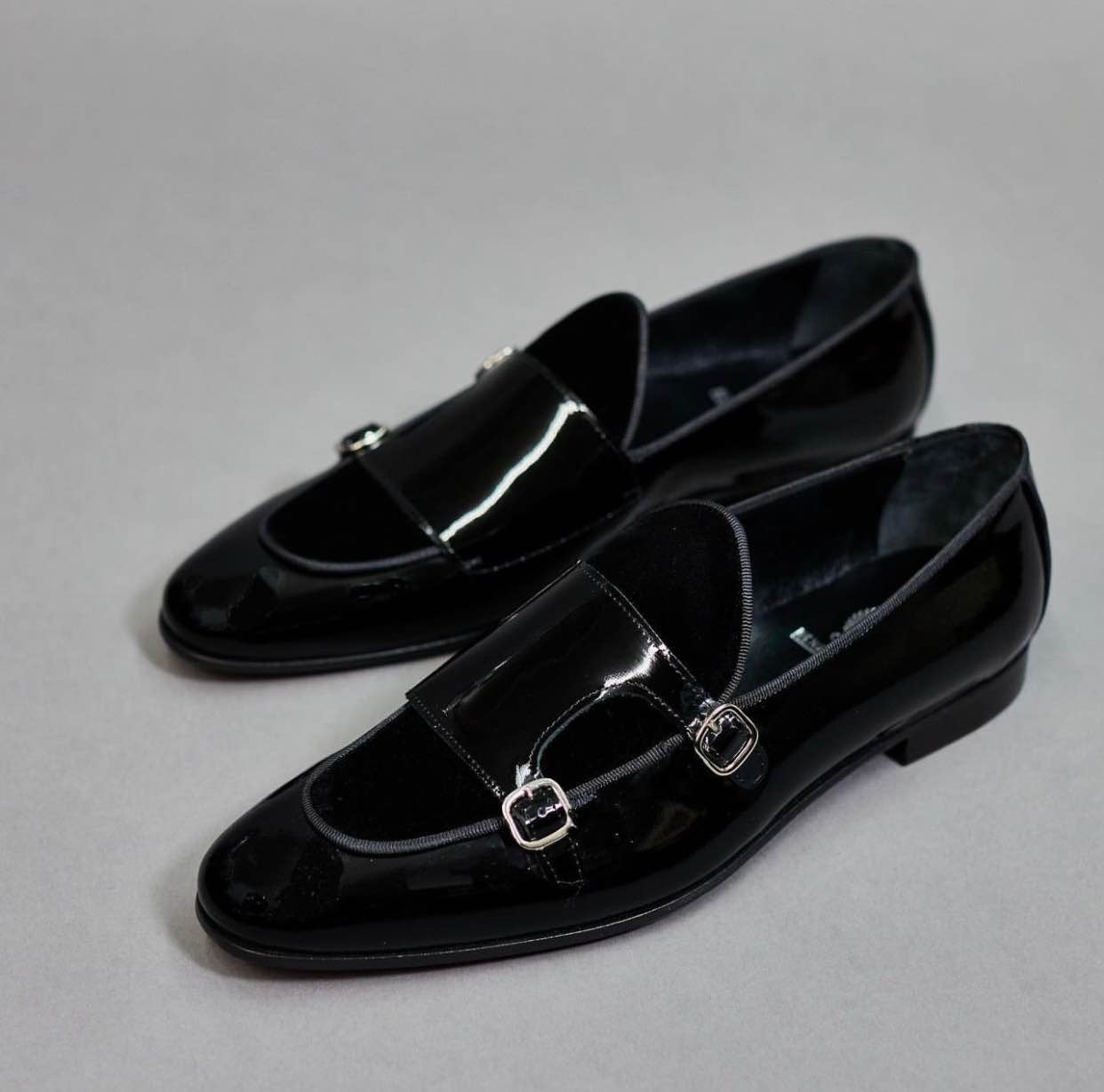 Pair of black patent leather loafers on a gray background