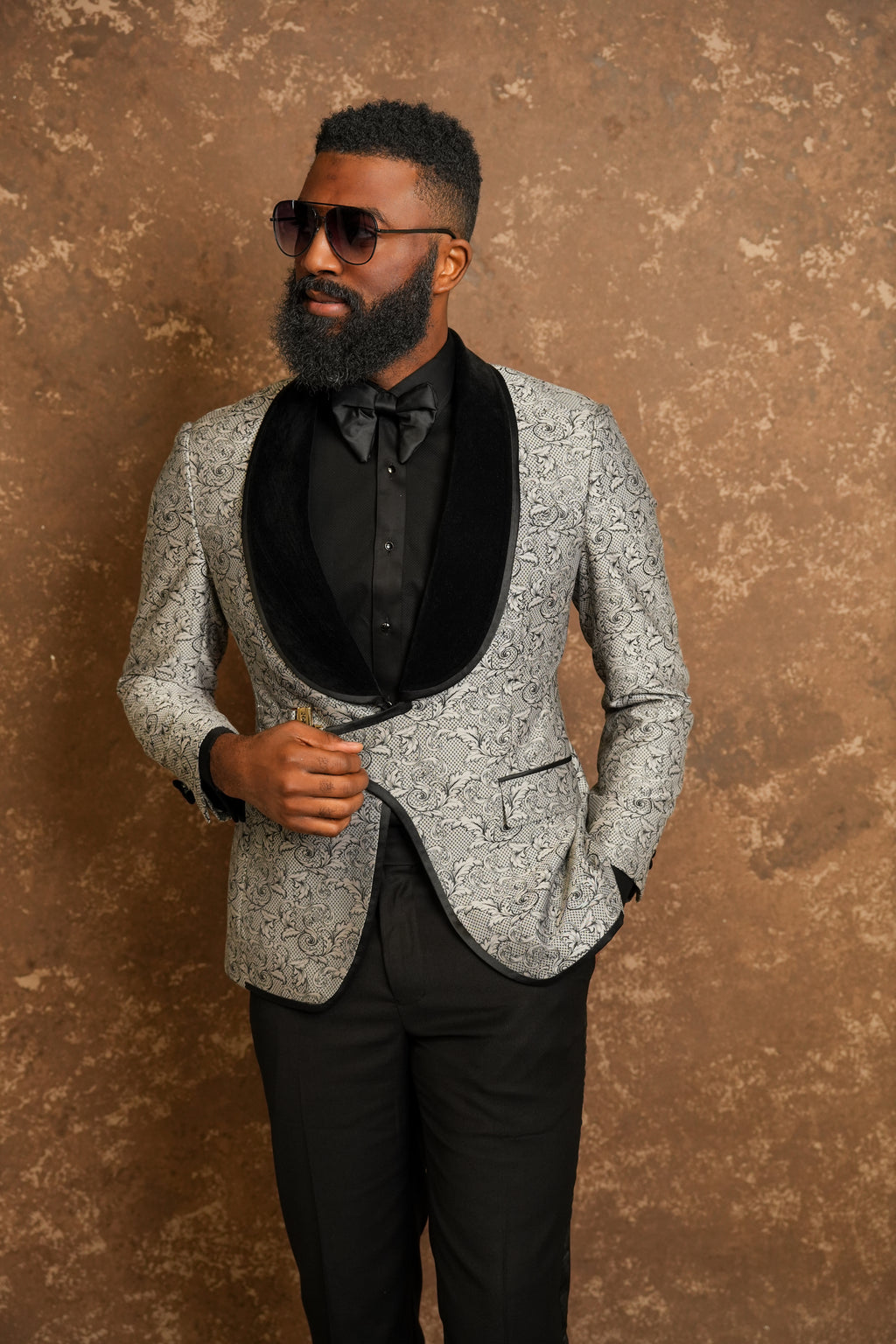 Man wearing a gray patterned tuxedo with a black tuxedo shirt 