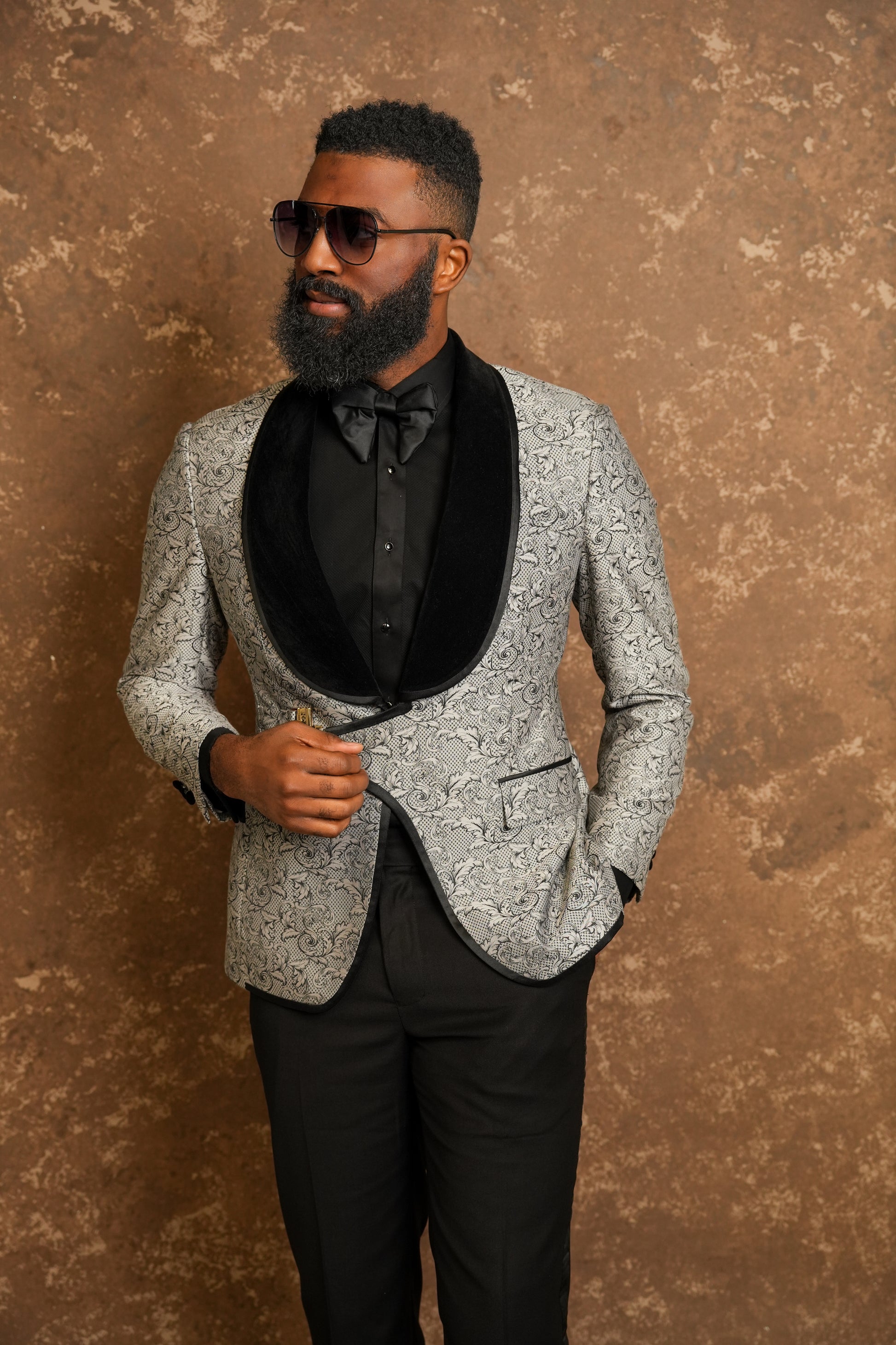 Man wearing a gray patterned tuxedo with a black tuxedo shirt 