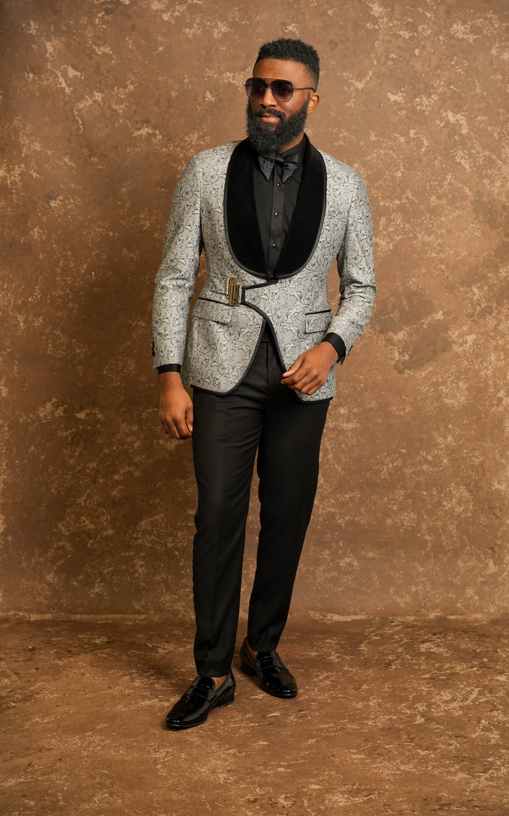 Man wearing a gray patterned tuxedo with a black tuxedo shirt 