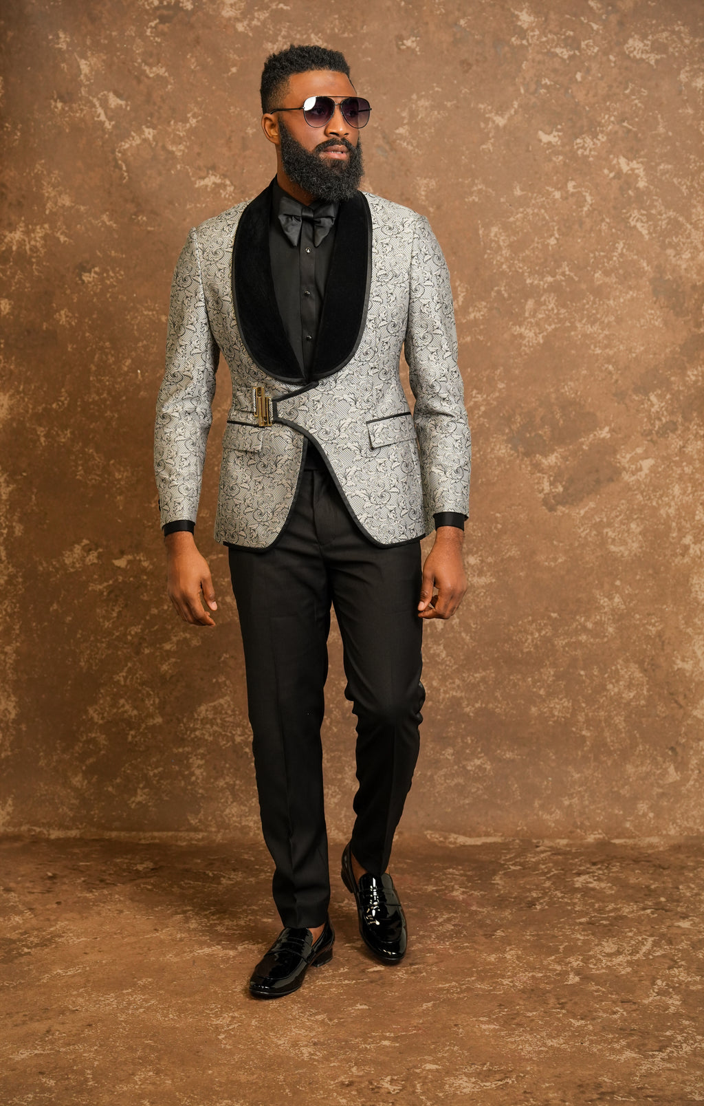 Man wearing a gray patterned tuxedo with a black tuxedo shirt 